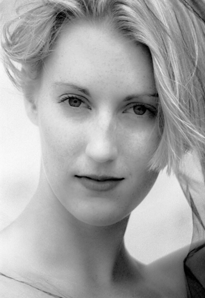 Black and white close-up portrait of a blonde woman with wind-swept hair