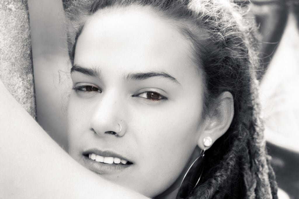 Black and white close-up portrait of a woman with dreadlocks and nose ring