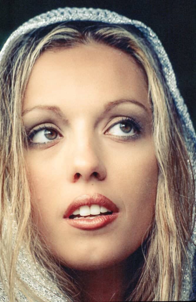Close-up portrait of a blonde woman in a silver veil looking upward
