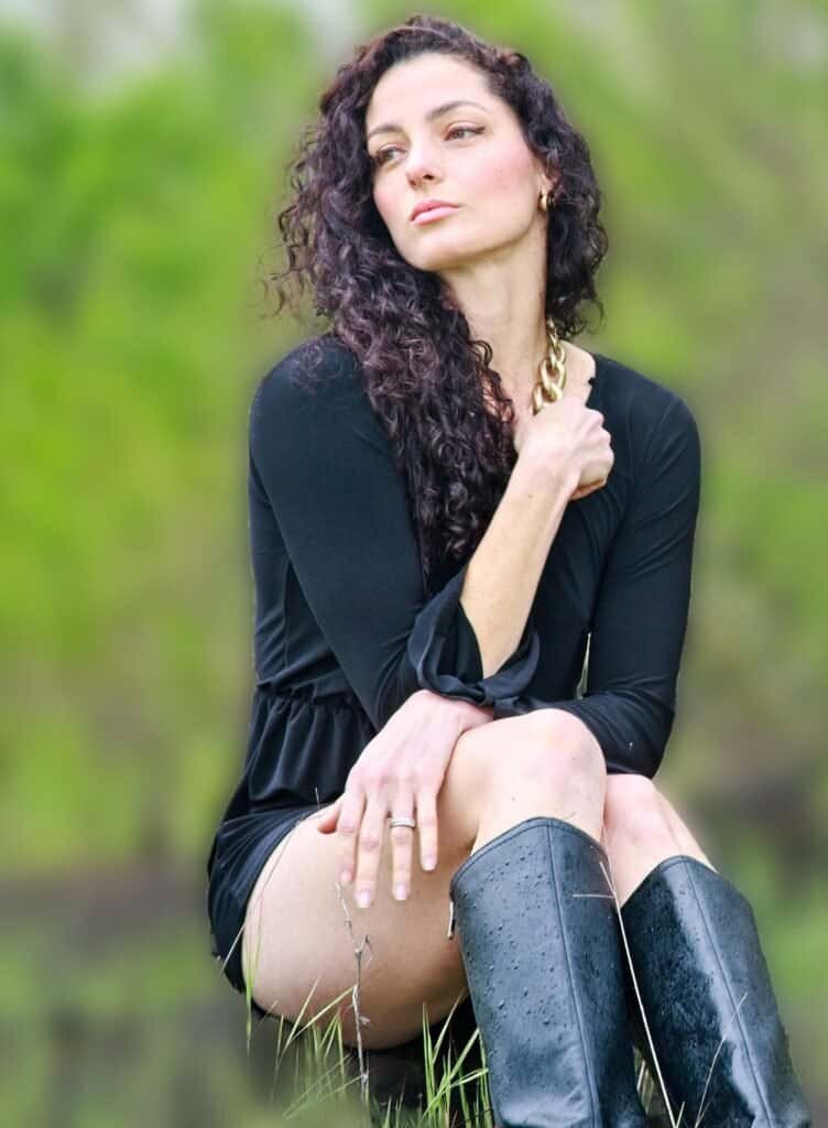 Natural light portrait of a woman with curly hair in a green outdoor setting, photographed by a Petaluma portrait photographer